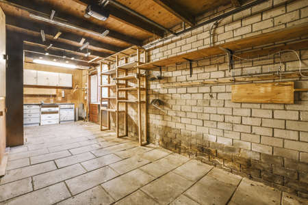 Spacious garage with closed white door and brick walls with hangers on itの写真素材