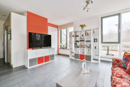 Interior of light living room with stylish furniture bookshelves,table,armchair decorations,dining...