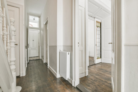 Interior of narrow corridor with telephone and radiator hanging on wall against stairway in daylight
