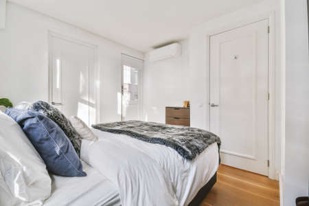 A spacious bedroom with a large bed and a fluffy, gray blanket in a modern house