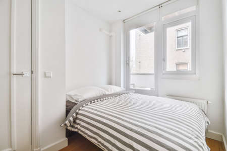 A spacious bedroom with a large bed and a striped bedspread in a modern house