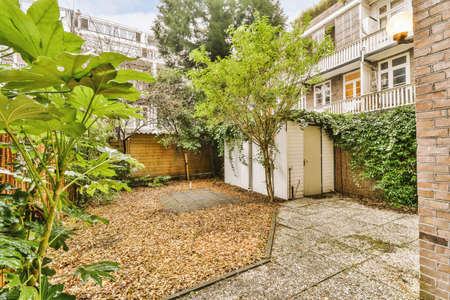 Neat paved patio with small garden near wooden fence