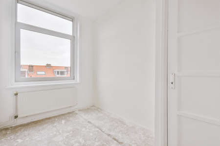 Plastic window and radiator on white wall in empty light room at homeの写真素材