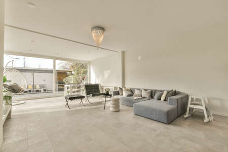 Interior of spacious room with stylish furniture against windows to balcony in contemporary...