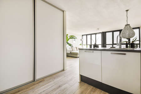 Interior of contemporary kitchen with stylish black cupboards and appliances near dining area in contemporary apartmentの写真素材