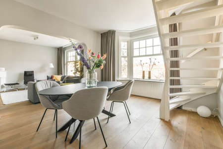 Table with chairs and flowers located under lamp against balcony entrance and lounge area in...