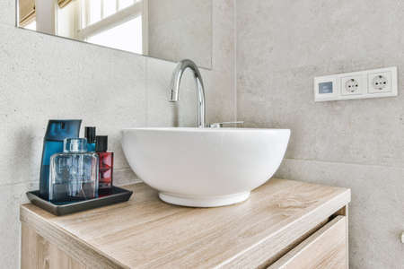 Sink with tap and liquid soap hanging on tiled wall under mirror in contemporary restroom at homeの写真素材