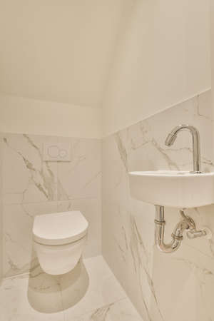 Sink base cabinet in white tiled bathroom with wall hung toilet