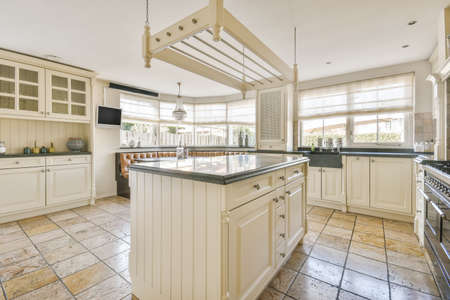 Interior of light kitchen and dining room with balcony doors in contemporary apartment at daytime
