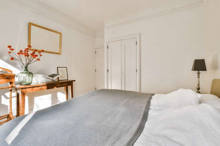 Minimalist interior design of small bedroom with soft bed placed in corner and wooden wardrobe and...