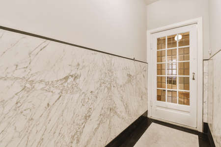 Light narrow hallway with many doors in white walls and glowing lamp over lumber floor
