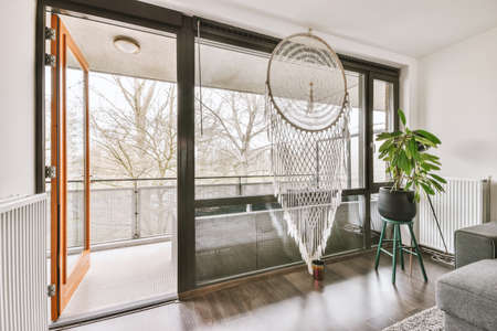 Large dreamcatcher on the window in the living room with grey sofa and stylish furniture