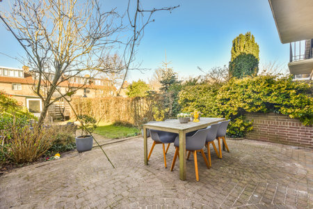 Neat paved patio with sitting area and small garden near wooden fence
