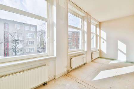 Plastic window and radiator on white wall in empty light room at home