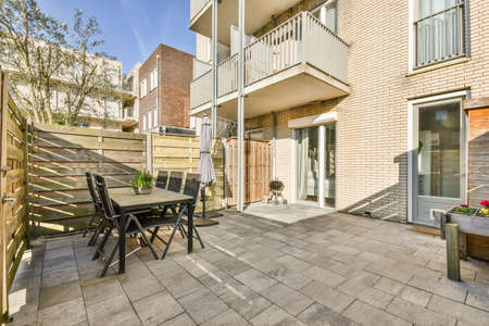 Neat paved patio with sitting area and small garden near wooden fence