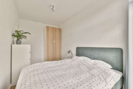 Home interior design of bedroom with bed and wooden wardrobe placed in corner near window in modern...
