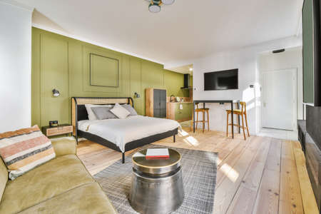 Home interior design of bedroom with bed and wooden wardrobe with sofa placed in corner near window...