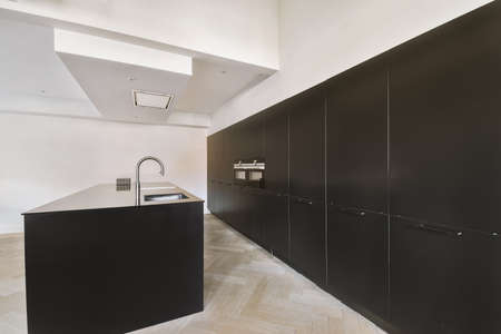 Interior of contemporary kitchen with stylish black cupboards and appliances near dining area in contemporary apartmentの写真素材