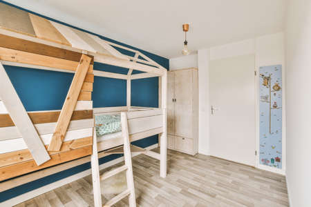 Minimalist interior design of small bedroom with two stored bed placed in corner and wooden wardrobe with sofaの写真素材