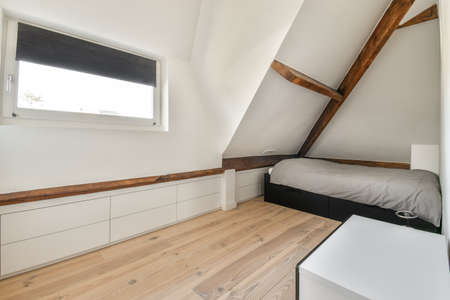 Interior of contemporary bedroom with white walls in attic of house