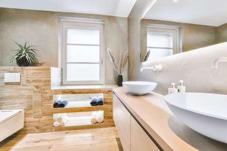 Shiny faucet installed on clean sink near mirror in modern bathroom at home