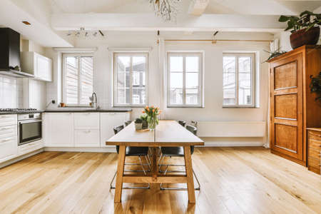 Stylish home interior design of dining zone with wooden table and chairs in modern apartment with...