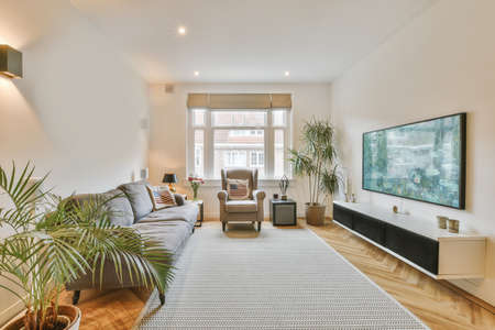 Open plan black kitchen in white living room with dining table and gray sofaの写真素材
