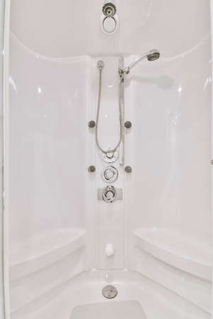 Shower tap and levers installed on white wall in modern spacious bathroom at home