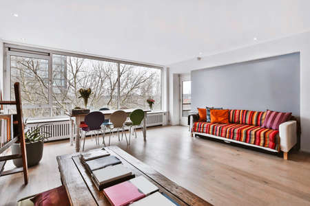 The interior of an amazing room with a long wooden table and books and ottomans