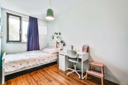 A delightful bedroom with a bed next to the window and a small tableの写真素材