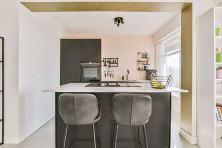 Wooden dining table under pendant lamp in open plan kitchen with living roomの写真素材