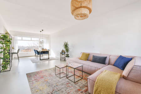 Wooden dining table under pendant lamp in open plan kitchen with living roomの写真素材