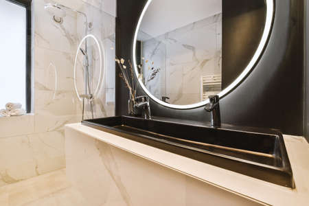 Sinks with mirrors and shower box with glass door in modern bathroom with white tiled walls