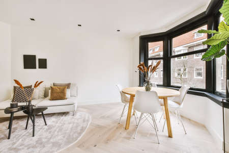 Contemporary open plan kitchen with dining table set and gray sofa in light spacious room