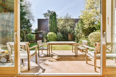 Neat paved patio with sitting area and small garden near wooden fence