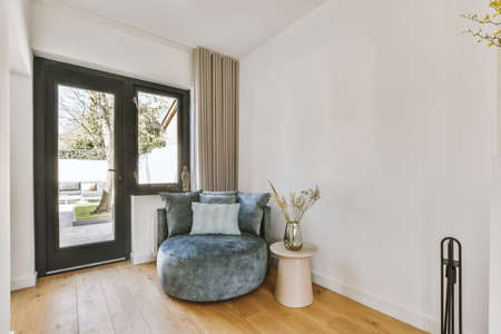 Comfortable sofa with cushions placed against light wall with TV and decorations in modern loving...