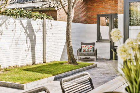 Neat paved patio with sitting area and small garden near wooden fenceの写真素材