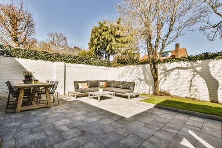 Neat paved patio with sitting area and small garden near wooden fenceの写真素材