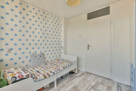 Interior of white room with children bed and blue wardope near window in daylightの写真素材