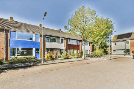 The front view of a brick building with signs, cars, pavement and wooden doors lead to the apartment