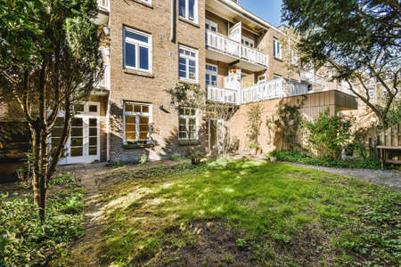 Neat paved patio with sitting area and small garden near wooden fence
