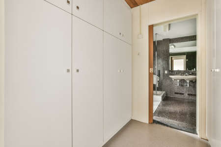 Comfortable bed with warm blanket located near window and door leading to terrace in stylish bedroom with grey wallsの写真素材