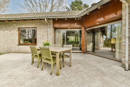 Neat paved patio with sitting area and small garden near wooden fence