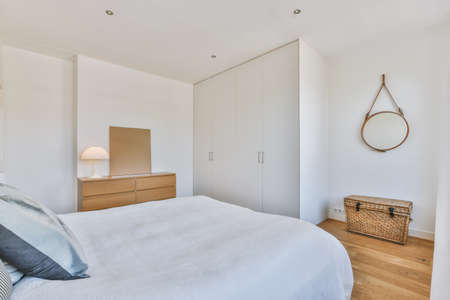 Home interior design of bedroom with bed and wooden wardrobe placed in corner near window in modern apartmentの写真素材
