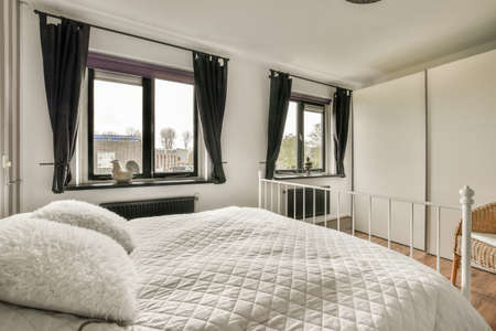 A spacious bright bedroom with a minimalistic bedside table and a large panoramic window