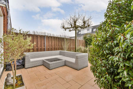 Neat paved patio with sitting area and small garden near wooden fence