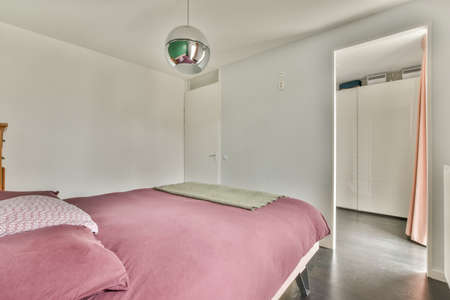 A spacious bright bedroom with a minimalistic stylish lamp and a large panoramic window