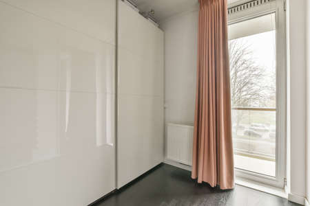 A spacious bright bedroom with a minimalistic stylish lamp and a large panoramic window