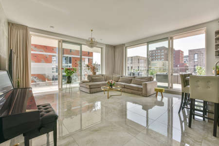 White cabinets with wooden counter of modern kitchen and dining table set in living room of apartmentの写真素材