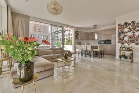 White cabinets with wooden counter of modern kitchen and dining table set in living room of apartmentの写真素材